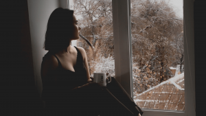 Woman staring oustide her window during fall