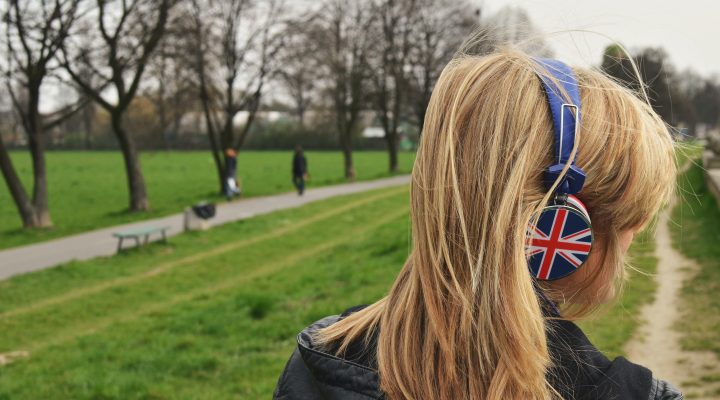 Woman walking in campus wearing headphones with England's flag